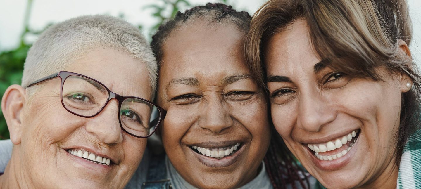 Three older women hugging and smiling