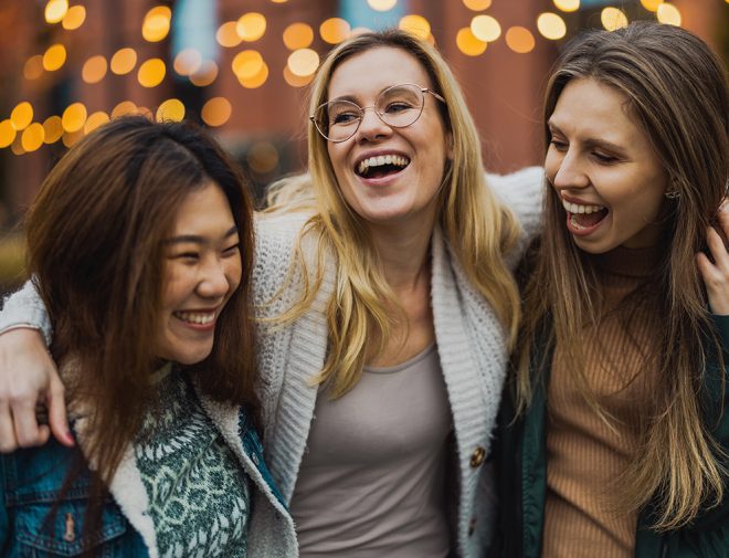 Three young women smiling and hugging