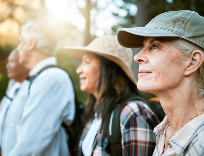 An older woman in a hat with a group of people hiking