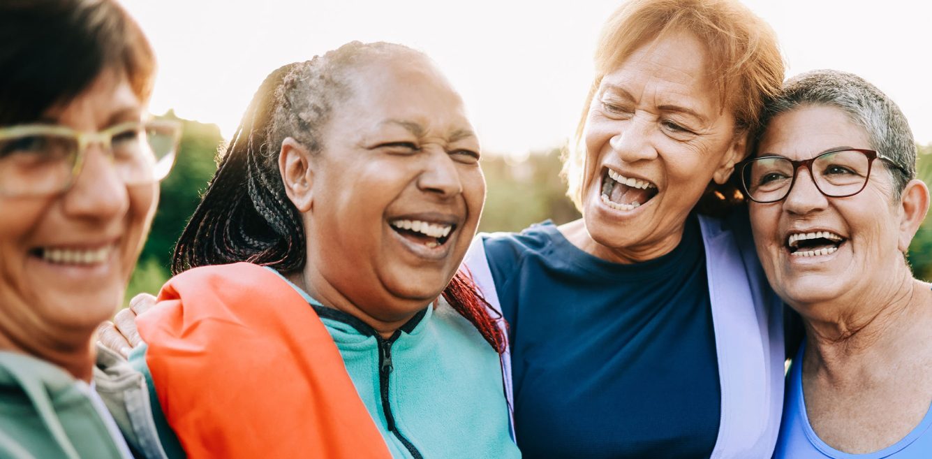 A group of older women in active wear smiling and hugging each other