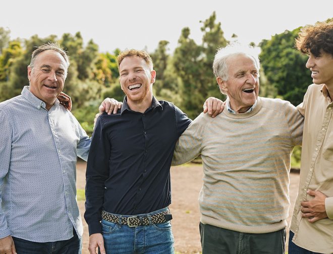 A group of men of varying ages hugging outside