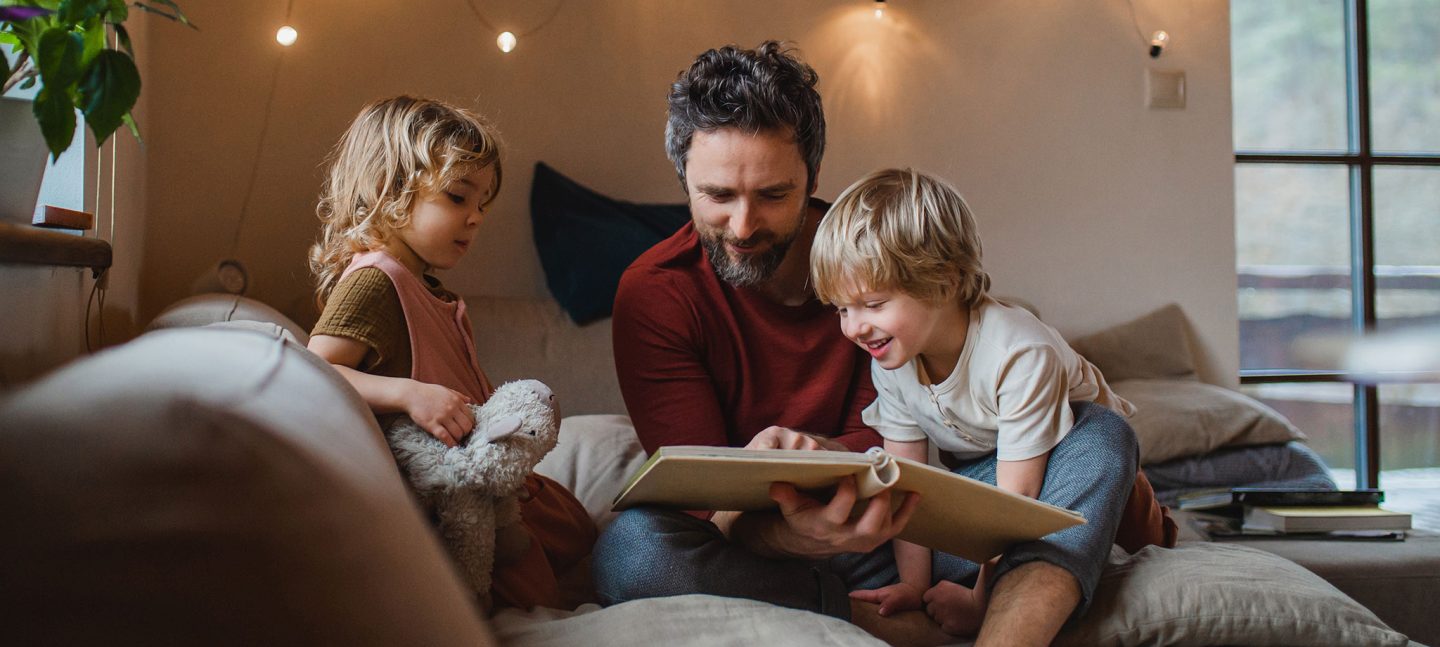 A man reading to his young son and daughter