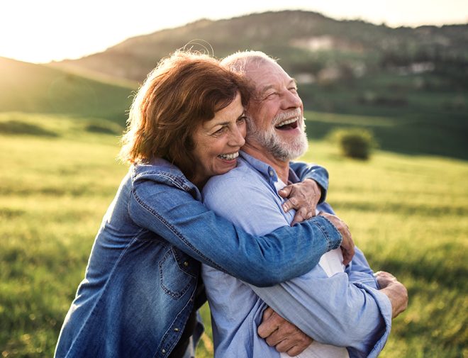 An older woman and a man hugging in a field