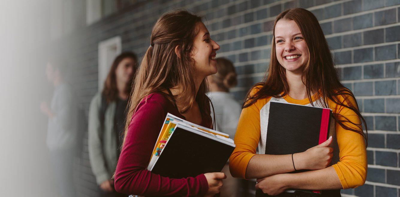 Two students walking with books in their hand