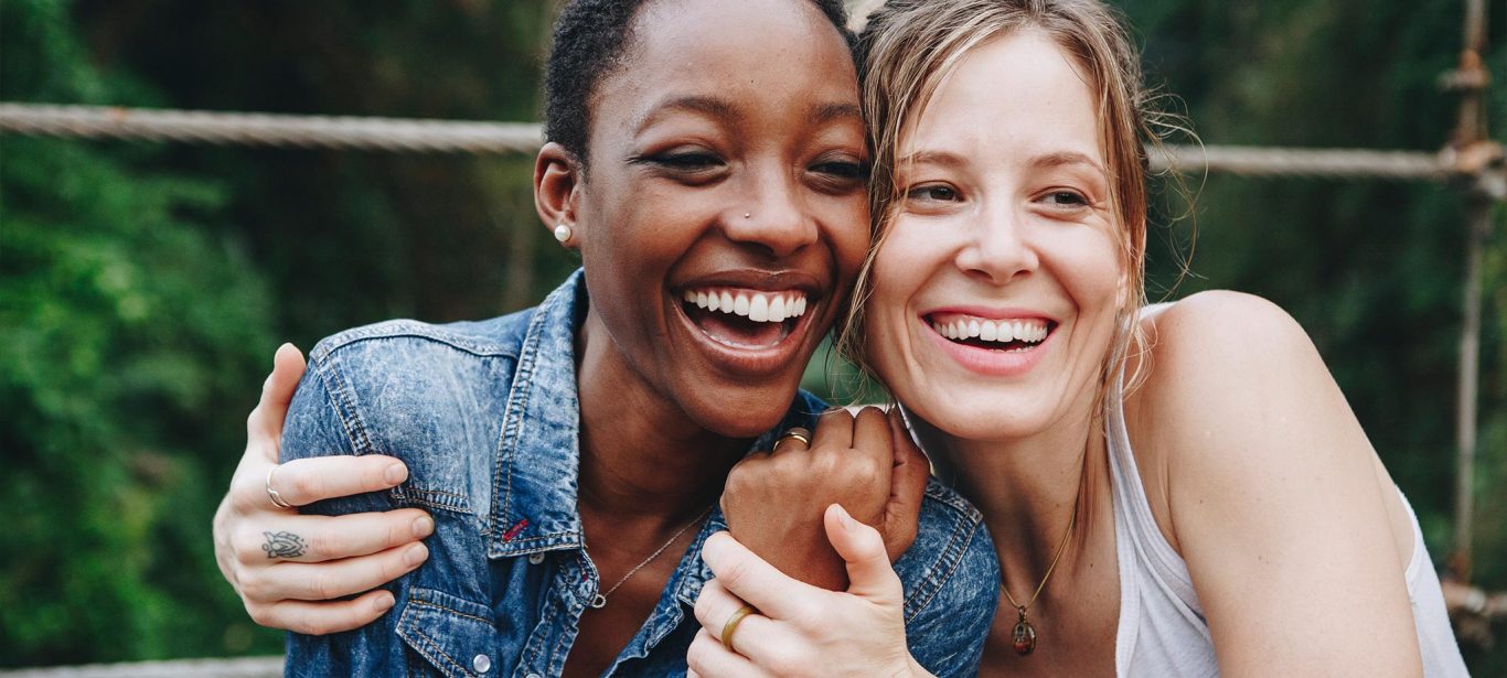 An african american woman and a caucasian woman smiling and hugging