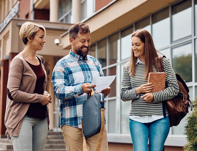 Three non-traditional students looking at a piece of paper and walking
