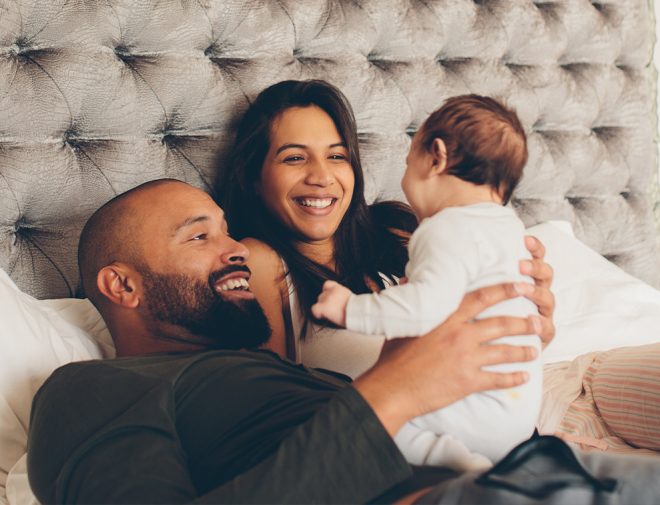 A man and a woman holding their baby in bed