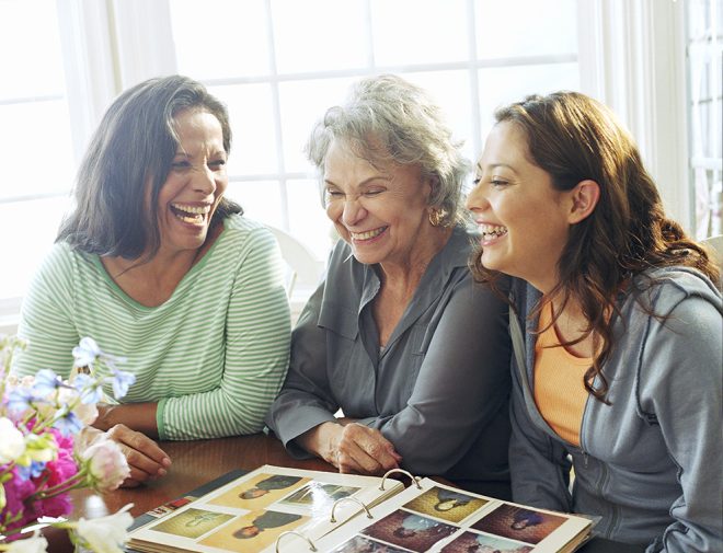 Multigenerational women smiling and looking at a photo album