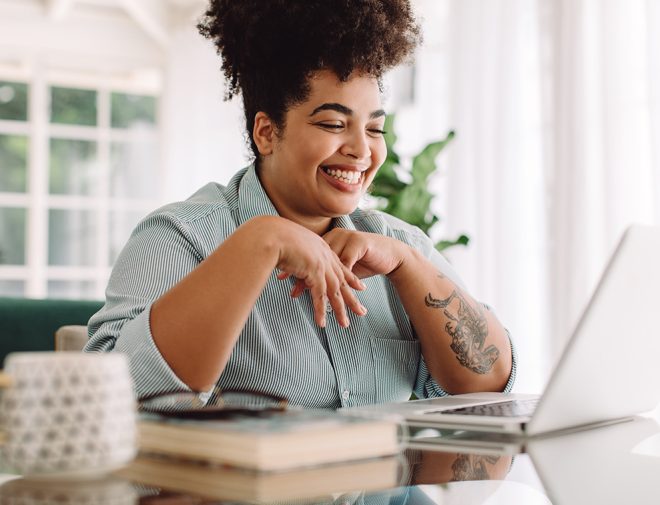 Image of a woman smiling at her laptop